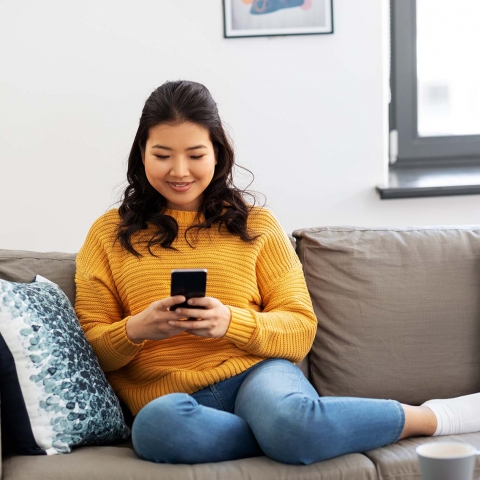Woman sitting on couch holding cellphone