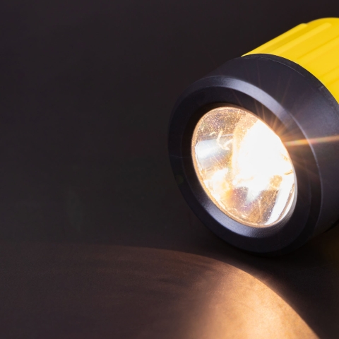 A lit yellow flashlight against a dark background