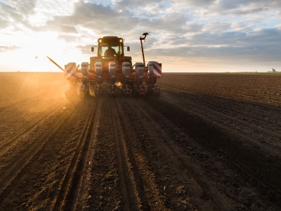Tractor planting in the field with the sun shining down on it