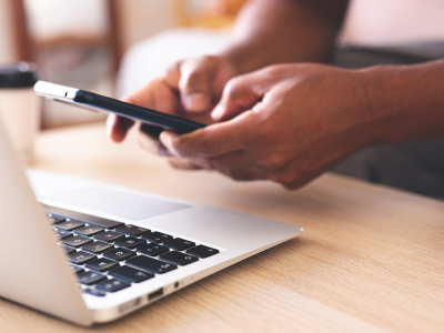 Hands on a cellphone over a laptop