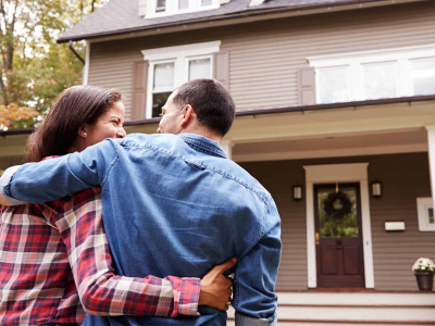 A couple standing in front of their home