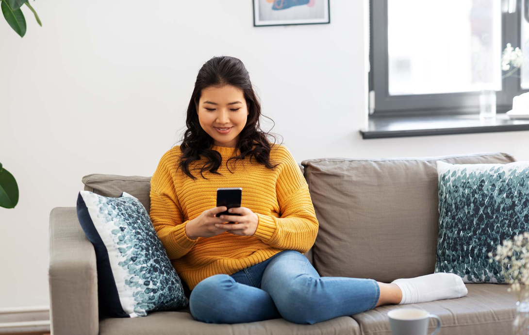 Woman sitting on couch holding cellphone