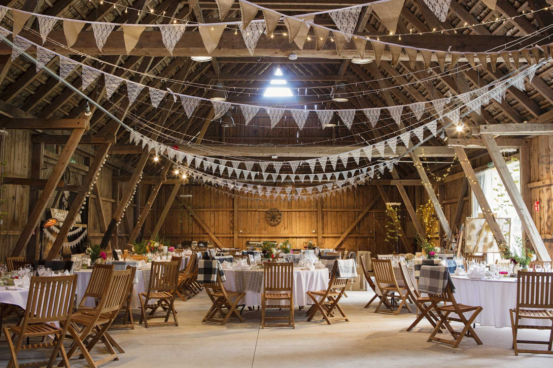 Tables and chairs set up in a barn for a wedding