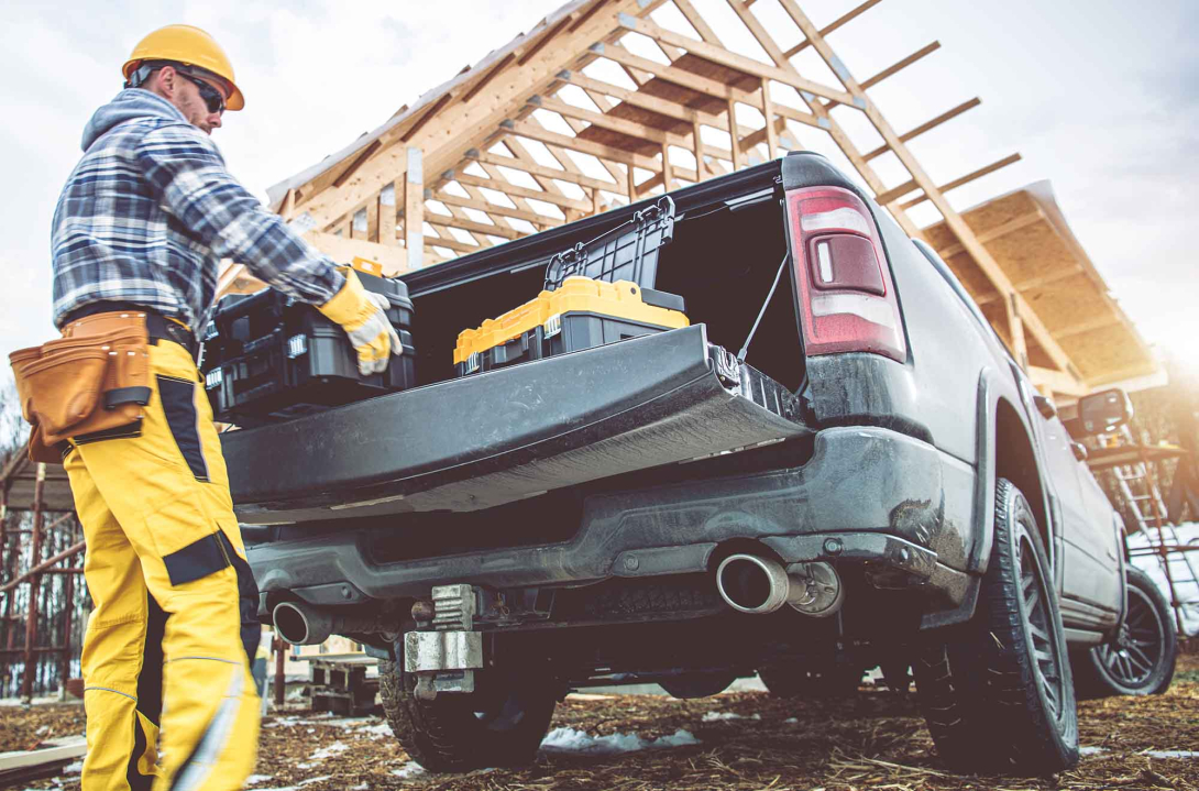 A worker unloading tools from a truck at a construction site