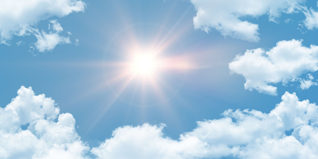A bright hot sun shining in a cloudy blue sky