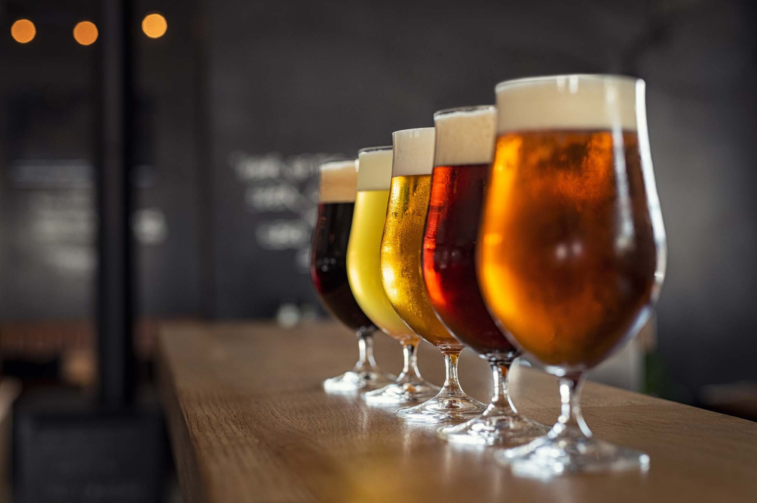 Glasses with different sorts of craft beer on wooden bar