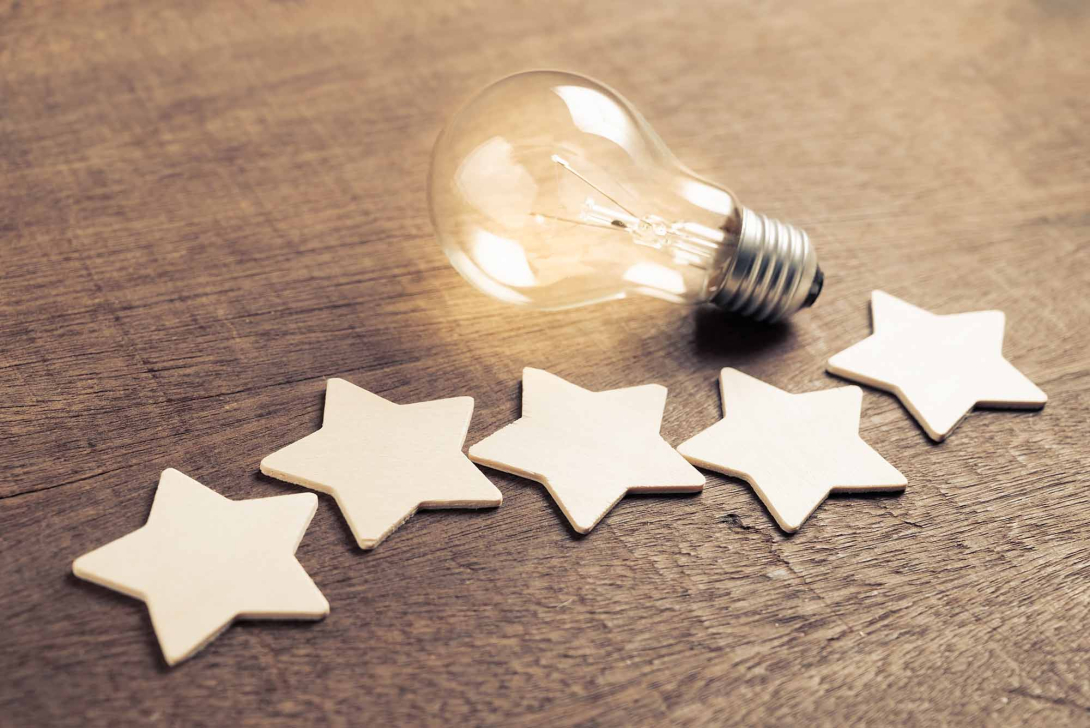 Five stars and a light bulb against a wood background