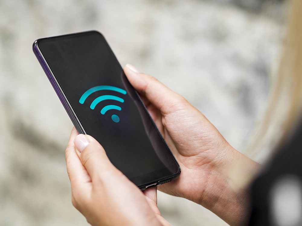 Hands holding a cellphone with a wifi symbol