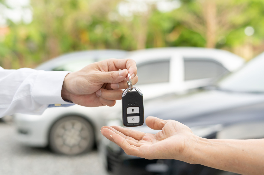 A person handing a set of new car keys to the purchaser