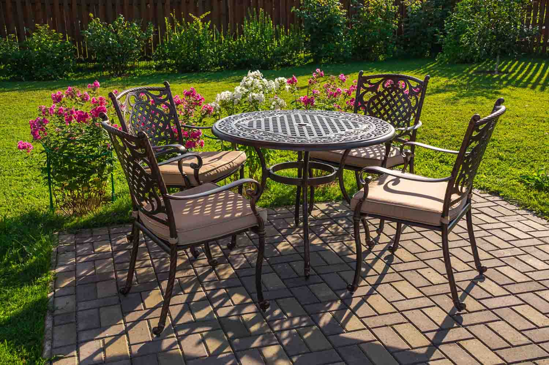 Outdoor furniture on a sunny patio surrounded by a bright green lawn