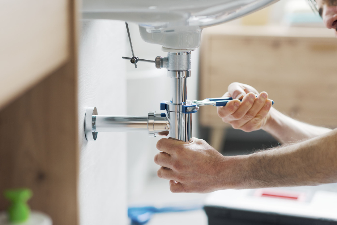 A plumber working on pipes underneath a sink